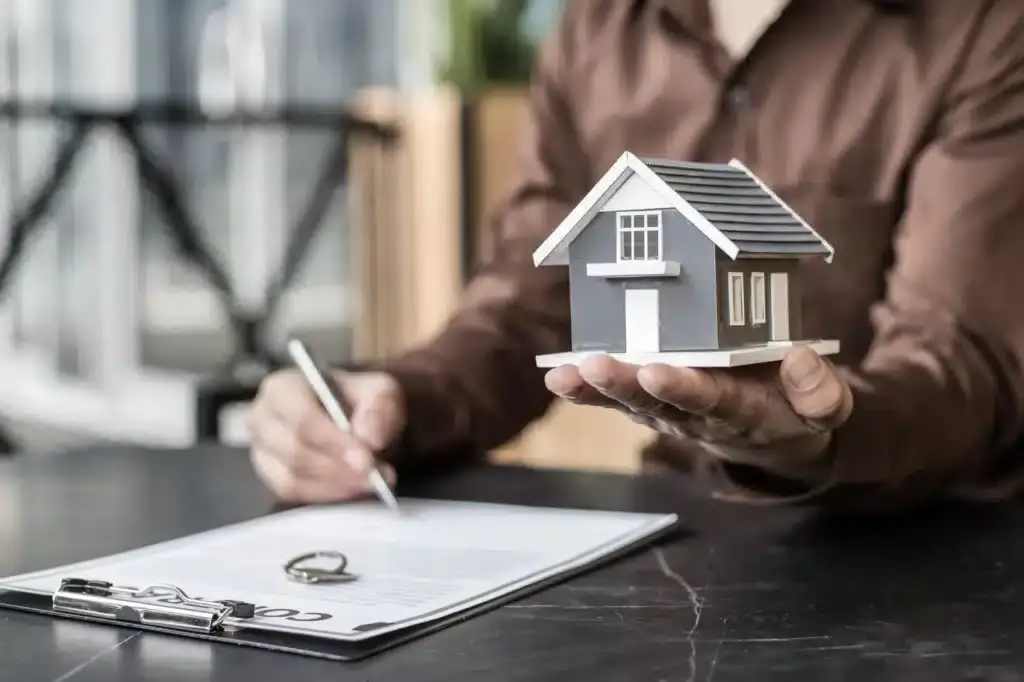 Person holding model house and contract